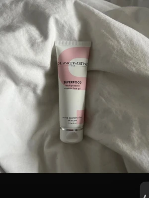 Dr. Ankerstjerne Superfood Face Gel - Multipurpose vitamin face gel från Dr. Ankerstjerne i en vit och ljusrosa tub. Gelen är framtagen som en aktiv skandinavisk hudvårdsprodukt och kommer i en smidig plastförpackning. Perfekt för dig som vill boosta huden med vitaminer. Oöppnad och oanvänd. Nypris 850kr