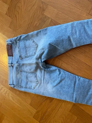 Ljusblå skinny jeans från Tiger of Sweden - Säljer ett par ljusblå skinny jeans från Tiger of Sweden med klassisk femficksmodell och skinnpatch bak i midjan. Jeansen har en snygg tvätt och smal passform som sitter tajt längs benen. Perfekta till en avslappnad och trendig look.