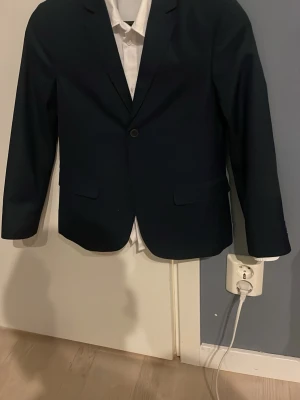 Mörkblå kostym storlek 140 slimfit passform  - Säljer denna kostym från hm i extremt bra skick. Har används en gång till ett bröllop. En vit skjorta kommer även med på köpet. Kavajen och kostymbyxorna är i storlek 140 och skjortan är i storlek 146. Hör av dig vid fler frågor. Mvh Philip 