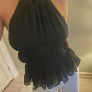 Svart halterneck topp med volang - Säljer en svart halterneck topp med volangkant och knyt i nacken och ryggen🤎