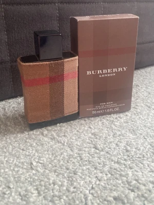 Burberry London Eau de Toilette 50ml - Burberry London Eau de Toilette för män i 50 ml flaska. Flaskan har en klassisk Burberry-rutig tygdetalj i beige, brunt och rött samt svart kork. Kommer med originalkartong i bruna nyanser med Burberry-logga. En stilren och tidlös parfym för dig som gillar elegans.