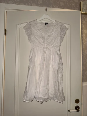 Vit spetsklänning från Vero Moda xs - Söt vit klänning från Vero Moda med v-ringning och spetsdetaljer upptill. Klänningen har volangärmar. Perfekt för varma dagar och somriga tillfällen. Även till fest eller student.