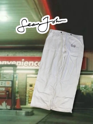 Vita baggy jeans från Sean John - Säljer ett par as feta vita baggy byxor från Sean John med SJ-logga och broderad lagerkrans på bakfickan. Byxorna har vida ben, hög midja och klassisk femficksdesign. Materialet ger en schysst streetwear-vibe. De är lite smutsiga. Längd 107cm, innerbenet 75cm, benöppning 27cm.