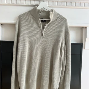 Half zip tröja - Säljer en grön stickad tröja från H&M med halv dragkedja vid halsen. Tröjan har lång ärm och en ribbad struktur, perfekt för lager-på-lager. Slim fit-modell som sitter snyggt på kroppen.