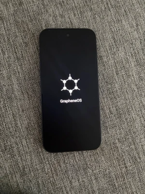 Google Pixel 9A - Säljer en svart Google Pixel med GrapheneOS installerat. Telefonen har en stilren design med rundade hörn, en bakre kamera och LED-blixt. Baksidan är matt och har ett diskret G-logotyp. Perfekt för dig som vill ha en säker och snabb Android-upplevelse.