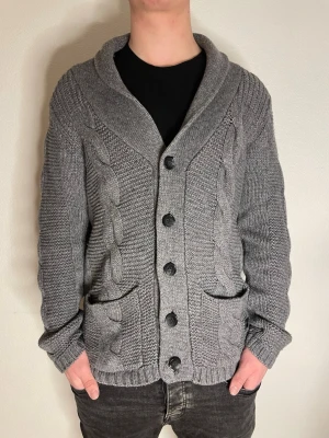 Snygg grå cardigan - Snygg grå cardigan i storlek Medium men passar mer som en Large. Modellen på bilden är 187cm! Hör gärna av er vid frågor eller funderingar!