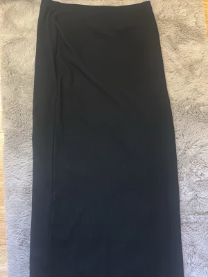 Svart ribbad långkjol  - En stilren svart långkjol med rak passform. Kjolen har en minimalistisk stil. Perfekt för dig som gillar klassiska plagg i garderoben.