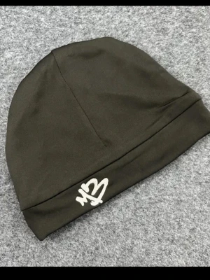Svart mössa med M3-brodyr - Snygg svart mössa med vit M3-brodyr framtill. Tillverkad i mjukt och stretchigt material som sitter skönt på huvudet. Perfekt för dig som vill ha en stilren och enkel accessoar med en unik detalj. 