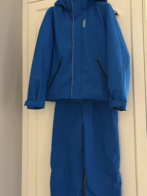 Blå täckbyxor med hängslen från Colmar  - Säljer ett blått kit från Colmar. Ett par täckbyxor och en jacka. Perfekta för kalla dagar i backen eller snölek. Ordinarie pris idag är 6600 kr. 
