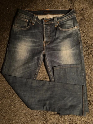 Nudie Jeans Grim Tim - Nudie Jeans i en riktigt snygg blå tvätt med snygga naturliga fades. Otroligt sköna jeans som bara blir snyggare ju mer de används! 📏 Mått: A: 38 cm B: 70 cm C: 95 cm. (OBS: Lappen säger L32, men kolla måtten noga då de är kortare än standard!) 📐 Passform: Slim straight, den perfekta passformen. ✅ Skick: 9/10 grymt skick. Sparsamt använda. Inga defekter alls. 🧩 Material: 98 % bomull, 2% Elestan. 💰 Nypris: ca 1600 kr. Pris ej hugget! ‼️Skickas samma dag eller dagen efter‼️