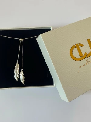 Silverhalsband med fjäderhängen CU - Säljer ett otroligt fint och unikt halsband i äkta återvunnet sterling silver (925). Halsbandet är justerbart I ändarna hänger två vackra, detaljrika fjädrar Smycket är stämplat med "925 ITALY" samt tillverkarens initialer "CJ" på baksidan av hänget. Kommer i sin tillhörande originalask från CJ Jewellery.   Material: Äkta sterling silver (Stämplat 925 Italy)  Märke: CU Jewellery Modell: Feather/Leaf double neck silver Nypris: Ca 1 950 kr på CU Jewellerys hemsida Skick: Mycket gott