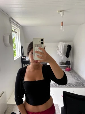Svart bolerotopp - Snygg svart bolerotopp med trekvartsärm och croppad passform. Perfekt att slänga över ett linne eller tubtopp för en trendig lager-på-lager-look. Tunn stickad känsla och enkel att matcha med olika outfits.