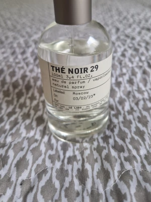 Le Labo Thé Noir 29 Eau de Parfum - Le Labo Thé Noir 29 är en exklusiv parfym i en stilren, genomskinlig glasflaska med metallock. Doften är inspirerad av svart te och har en modern, minimalistisk design. Flaskan rymmer 100 ml och etiketten har en personlig touch med detaljer om tillverkning.