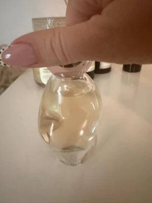 Cosmic parfym av Kylie Jenner 50 ml - Säljer en Cosmic Eau de Parfum från Kylie Jenner. Flaskan är genomskinlig med en mjukt rundad form och ett ljusrosa lock. Innehållet är ljust gult. Perfekt för dig som gillar trendiga dofter och snygg design på parfymflaskan.