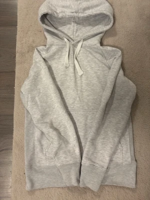 Ljusgrå hoodie från Russedress - Snygg ljusgrå hoodie från Russedress med klassisk huva och dragsko. Hoodien har magficka och ribbade muddar vid ärmslut och nederkant. Perfekt för en avslappnad och stilren look.
