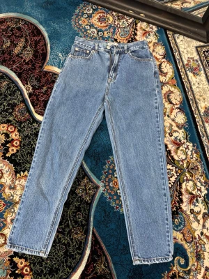 Blå mom jeans från Pull&Bear - Säljer ett par klassiska blå mom jeans från Pull&Bear. Jeansen har hög midja, raka ben och fem fickor. Tillverkade i ett robust denimtyg med snygg tvättad look. Perfekta för en avslappnad och trendig stil.