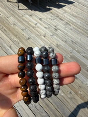 Naturstensarmband bundle x5 - Snygga armband med runda pärlor i olika färger som brunt, svart, vitt och grått. Varje armband har en metallisk cylinderformad pärla som detalj. Perfekt accessoar för att lyfta din stil med en cool och modern känsla.