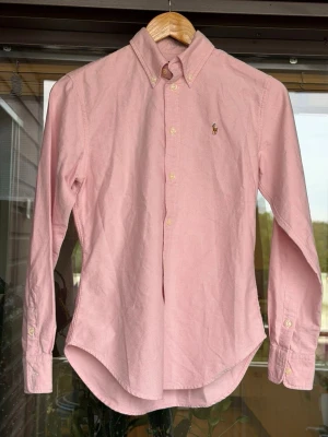 Rosa Ralph Lauren skjorta - Skön rosa Raulph lauren skjorta som sitter bra, jättebra skick, har själv knappt använt den för den är för liten för mig. Skriv vid funderingar!