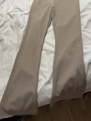 Beige utsvängda leggings - Snygga beige leggings med utsvängda ben och hög midja. Mjukt och stretchigt material som sitter skönt på kroppen. Perfekta för en trendig och avslappnad look.