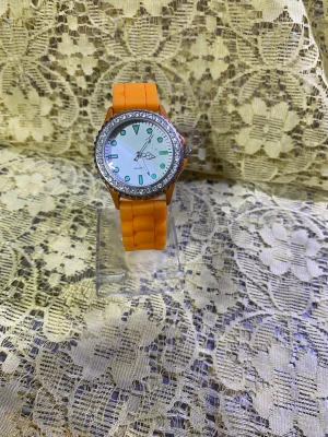 Orange klocka med glittrande ram - Stilren klocka med orange silikonarmband och en rund urtavla. Ramen runt urtavlan är dekorerad med glittrande stenar och urtavlan är vit med tydliga markeringar. Perfekt accessoar för dig som vill sticka ut. Nya klocka med nya batteri 