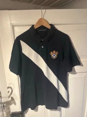 Polo Ralph Lauren piké  - Mörkblå Piké från polo Ralph Lauren med ett vitt diagonalt sträck och broderat märke på bröstet Storlek XL men passar L mer Mycket bra skick utan tecken på slitage.  Skriv vid frågor och funderingar. Priset är ej hugget i sten! Kolla även min profil för mer!