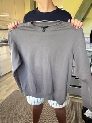 Grå loose fit sweatshirt från H&M - En enkel och stilren grå sweatshirt från H&M i loose fit-modell. Tröjan har rund halsringning, ribbade muddar vid ärmslut och nederkant samt är tillverkad i mjukt bomullsmaterial. Perfekt för en avslappnad och trendig look.