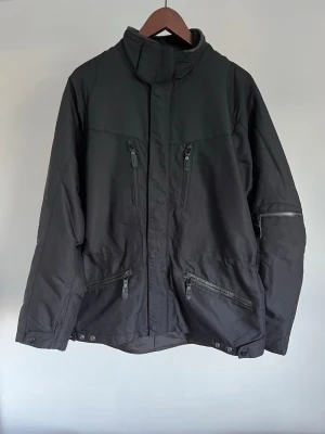 Polo by Ralph Lauren Utility/Field Jacket - Polo by Ralph Lauren Utility/Field Jacket Storlek: M Passform: Regular Fit Krage: Hög ståkrage  Material: Polyester/Nylon Mått: Bröstvidd 108 cm, längd 74 cm, axel 48 cm Skick: Jackan är i ett väldigt fint skick utan defekter  Nypris cirka: 3 000 kr