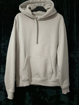 Beige mjukisset från Zara (Hoodie & Mjukisbyxor) - En clean beige hoodie med huva och dragsko. Hoodien har en stor magficka och ribbade muddar vid ärmslut och nederkant. Tillverkad i mjuk bomullsblandning för en skön och avslappnad stil. Perfekt för dig som gillar en enkel och stilren look. Både hoodie och byxor är storlek S men hoodie passar även M