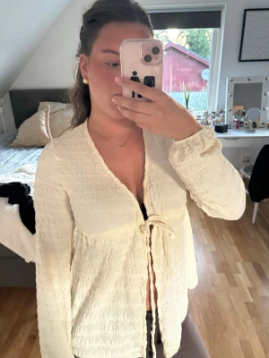 Ljus cremefärgad topp - Säljer en ljus cremefärgad omlottopp med lång ärm och knyt framtill💕💕är som en S