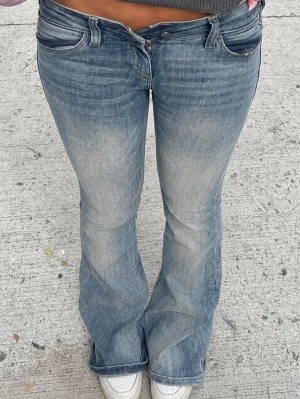 Blå bootcut jeans från Cheap Monday - Säljer ett par blå bootcut jeans från Cheap Monday med låg midja och slitna detaljer. Jeansen har klassisk femficksmodell och en stor vit patch med Cheap Monday-loggan bak. Perfekta för en avslappnad och trendig look. sista bilden visar slitningar, strl 29/32 men passar S/M