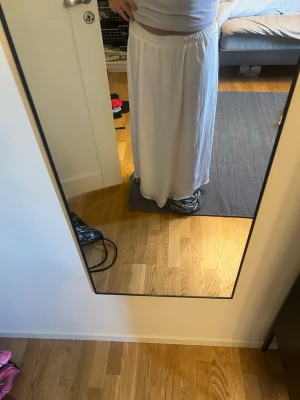Vit långkjol i bomull - Säljer en enkel och flowy vit långkjol i mjukt bomullsmaterial. Kjolen har en bred resår i midjan för skön passform och faller snyggt längs benen. Perfekt till sommaren för en avslappnad och stilren look. Jätteskönt material, endast andvönt 1 gång 