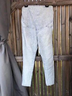 Ljusblå mammajeans med hög midja - Säljer ett par ljusblå mammajeans med hög, stretchig midja som ger extra stöd över magen. Jeansen har en tvättad look, raka ben och klassiska bakfickor. Perfekta för dig som vill ha både stil och komfort under graviditeten.