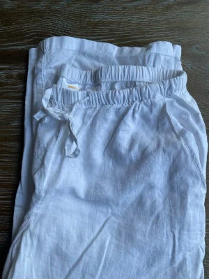 Vita linnebyxor med dragsko - Snygga och luftiga vita linnebyxor. Byxorna har avslappnad passform och sidofickor, perfekta för en chill och stilren look. Perfekt för en sommar med Stockholm stil.
