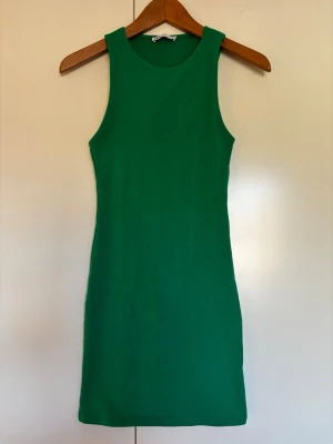 Grön ärmlös kort trikåklänning från Zara storlek S - passar även XS - Snygg grön klänning i kort modell med ärmlös design och rund halsringning. Klänningen har en enkel och stilren look. Materialet stretchig bomull. Från Zara storlek S - passar även XS