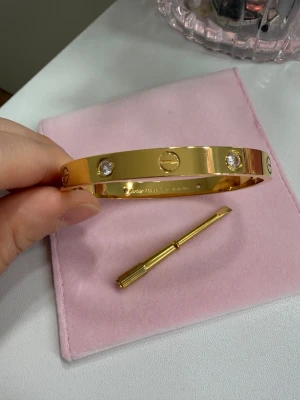 18k guldpläterat armband  - Ett stilrent och tidlöst armband tillverkat av rostfritt stål och pläterat med 18K guld. Den eleganta designen gör det till ett perfekt basarmband som enkelt kan matchas med alla dina favoritaccessoarer. Bär det ensamt för en minimalistisk look eller kombinera det med andra armband för en personlig stil. it Rostfritt stal it 18K guldplatering f Stamplat it Tidlos och lattmatchad design , Finns i storlek 18 cm t Passar både vardag och fest Kolla bifogade bilder