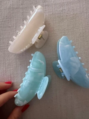 Pastellfärgade hårklämmor i plast - Säljer tre stora hårklämmor i pastellfärger: en i ljusbeige, en i mintgrön och en i ljusblå. Klämmorna har en glansig, marmorerad finish och är tillverkade i plast med metallfjäder. Perfekta för att snabbt sätta upp håret med stil.