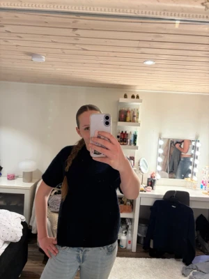 Svart stickad kortärmad topp - En svart stickad topp med korta ärmar och rund hals. Modellen är rak och enkel, vilket gör den lätt att matcha med olika outfits. Perfekt för dig som gillar en stilren och basic look.