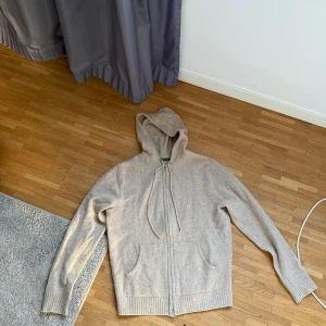 Beige hoodie från Stenströms - Mysig beige hoodie från Stenströms i mjukt stickat material. Tröjan har dragkedja framtill, huva med dragsko och ribbade muddar vid ärmslut och nederkant. Perfekt för en avslappnad och stilren look.