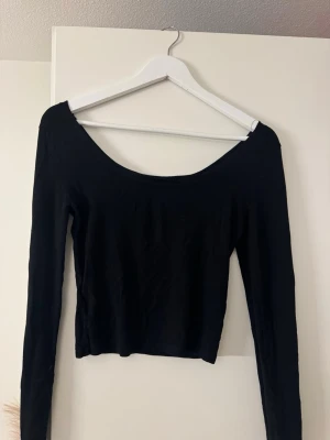 Svart croppad långärmad topp - En svart, croppad långärmad topp med bred urringning. 