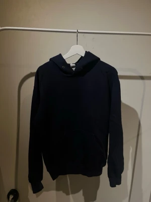 Mörkblå hoodie - En stilren mörkblå hoodie från Fruit of the Loom i klassisk modell. Tillverkad i mjukt bomullsmaterial som är skönt att bära. Perfekt för en avslappnad look. M/S