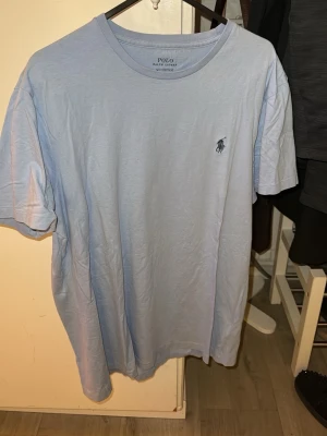 Ljusblå t-shirt från Polo Ralph äkta Lauren - Snygg ljusblå t-shirt från Polo Ralph Lauren med klassisk logga broderad på bröstet. Modellen är custom slim fit och har rund halsringning samt korta ärmar. Perfekt för en stilren och avslappnad look.