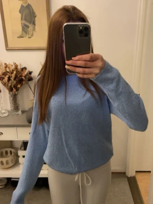 Ljusblå stickad tröja - Mysig ljusblå stickad tröja med rund hals och långa ärmar. Tröjan har en enkel och clean design med ribbade muddar vid ärmslut och nederkant. Perfekt att matcha med både jeans och mjukisbyxor för en chill look.