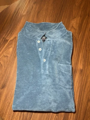 Blå frotté polotopp från Robbie Moor - Blå polotopp från Robbie Moor i mjuk frotté. Använd fåtal gånger, i toppskick!