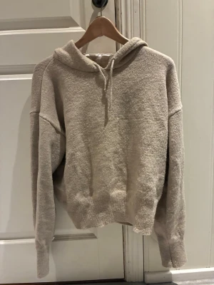 Beige stickad hoodie från Gina Tricot - Mysig beige stickad hoodie från Gina Tricot med huva, inga tecken på använding, säljs då jag inte har användning av den💕