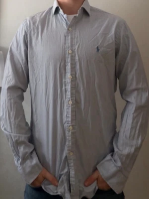 Blårandig skjorta från Polo Ralph Lauren - Klassisk blårandig skjorta från Polo Ralph Lauren i slim fit-modell. Skjortan har knappar framtill, lång ärm och den ikoniska broderade loggan på bröstet. Tillverkad i tunn bomull som känns skön mot huden och passar perfekt till lager på lager. Skick9/10!✅