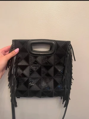 Maje väska med fransar  - Skitcool maje väska med mönster i olika material. Dessvärre små defekter på axel bandet som man kan se på bild 6. Väskan kommer med dustbag. Original pris ligger på runt 3200kr🩷