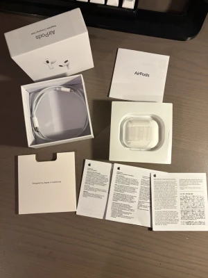 Apple AirPods med MagSafe-laddning - Säljer ett par vita Apple AirPods med MagSafe-laddningsetui. Trådlösa in-ear hörlurar i stilren design, tillverkade i plast. Levereras med originalkartong, laddningskabel och manualer. Perfekta för musik, samtal och smidig anslutning till Apple-enheter.
