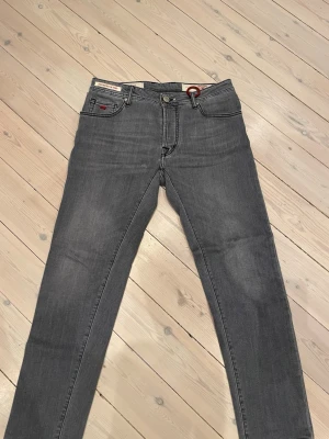 Tramarossa Brando jeans herr - Snygga grå jeans från tramrossa, modell Brando. Nypris ca. 5000kr men säljer nu dessa för under tusenlappen! Klassisk femficksdesign med raka ben och normal passform. Jeansen har en diskret tvätt och röda detaljer vid linningen. Perfekta till en avslappnad stil och tillverkade i mjukt bomullsmaterial.