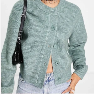 Grön ribbstickad kofta  - Mysig grön kofta från Weekday med ribbstickad struktur och rund halsringning. Koftan har långa ärmar och stängs med fem knappar framtill. Perfekt att slänga över en t-shirt eller linne för en chill look💚