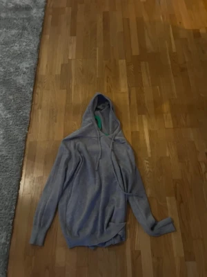 Grå Kashmir hoodie - En enkel och stilren grå hoodie med huva och dragsnören. Hoodien har långa ärmar och ribbade muddar vid ärmslut och nederkant. Perfekt för en avslappnad och casual look.